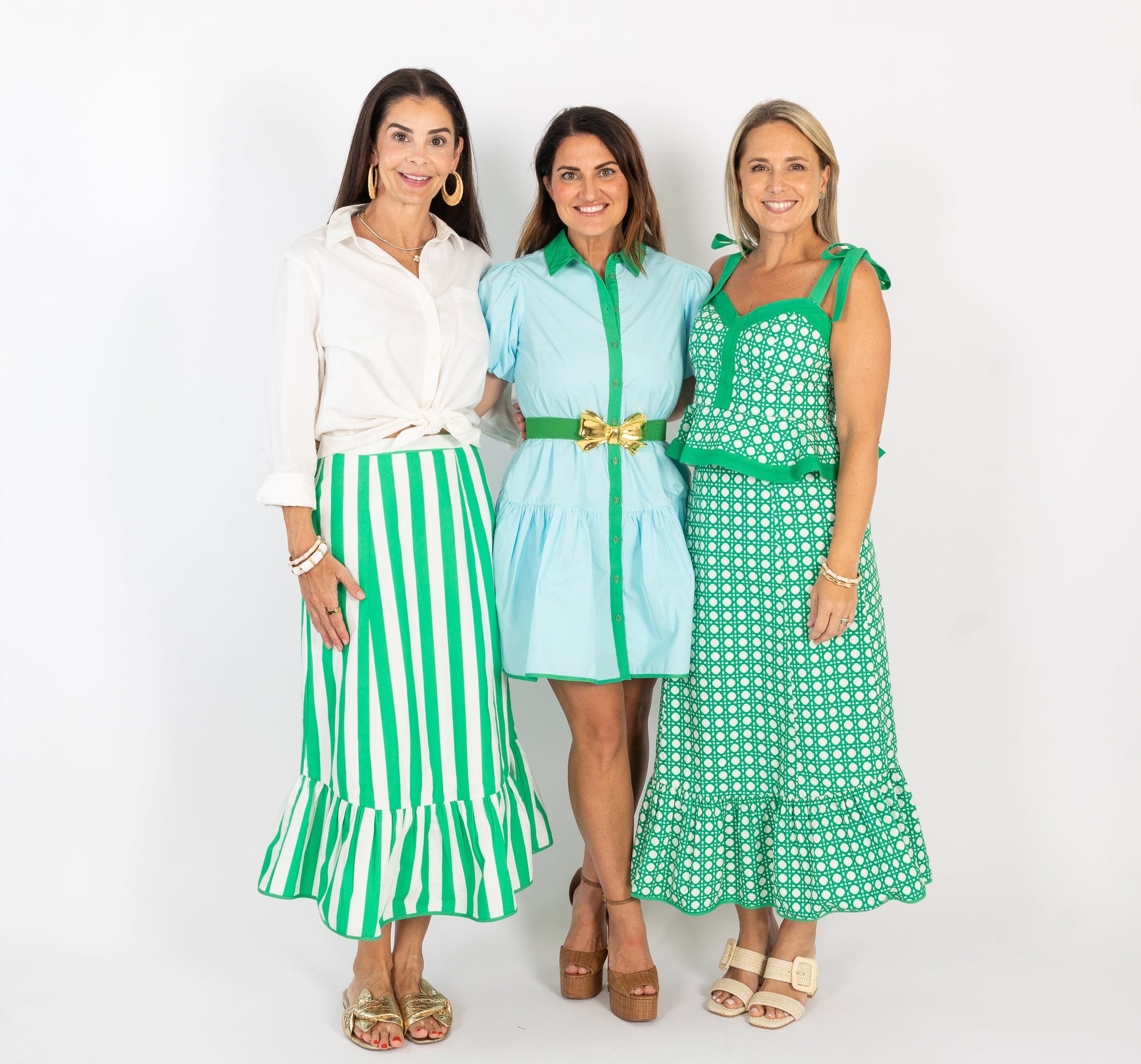 Three women wearing green and white outfits on a white background