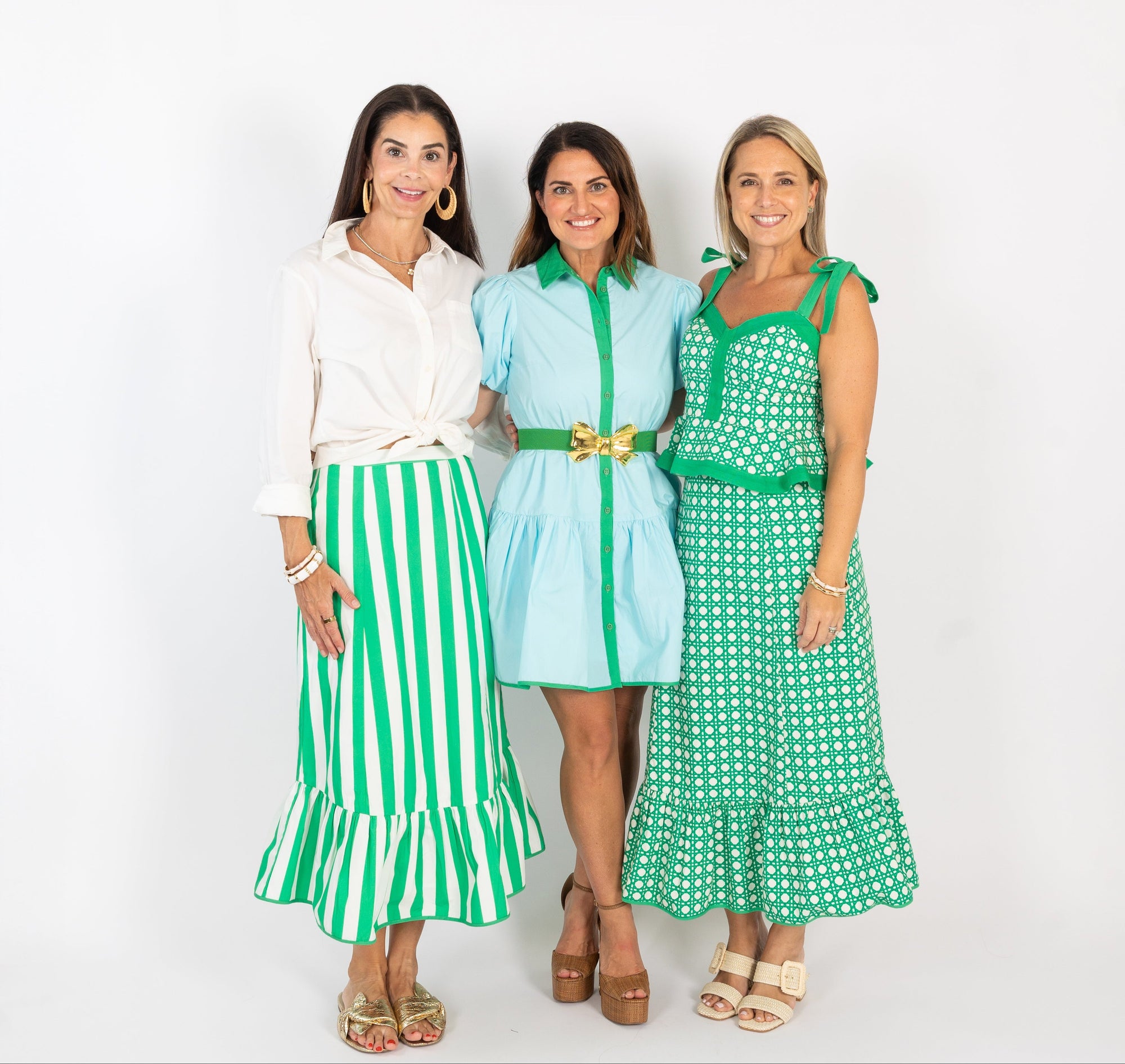 Three women wearing green and white outfits on a white background