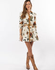 Woman wearing a floral dress with a belt and brown boots on a white background