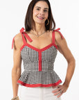 Woman wearing a black and white checkered top with red accents on a white background