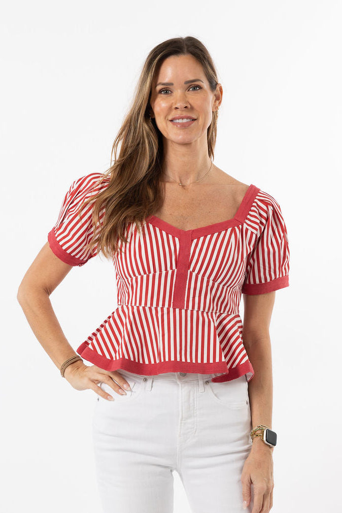 Woman wearing a red and white striped top with a plain background