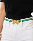 Person wearing a black top, white pants, and a green belt with a gold bow buckle on a white background