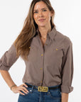 Woman wearing a brown button-up shirt and blue jeans on a white background