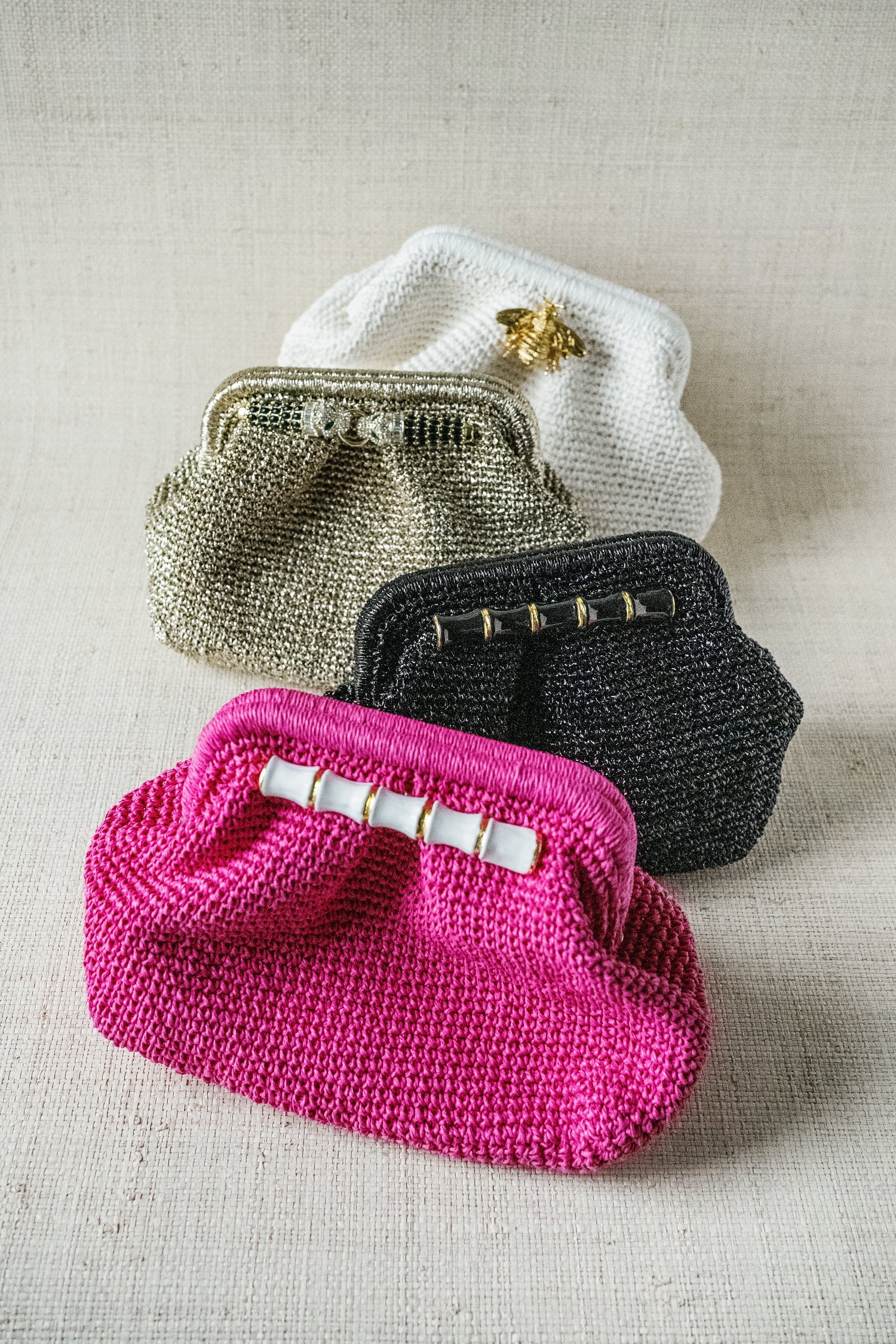 Three small handbags in pink, black, and white on a textured surface